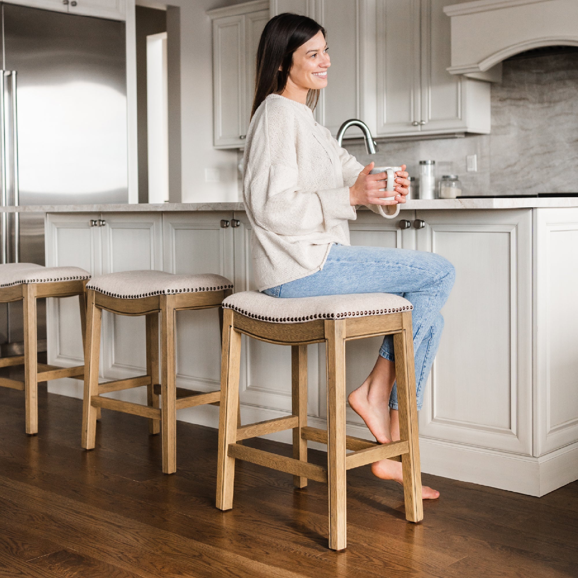 Adrien Saddle Counter Stool in Light Brown Finish and Natural Fabric Upholstery in Stools by Maven Lane
