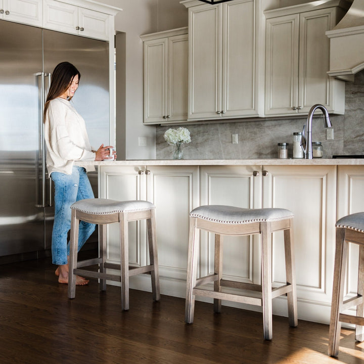 Adrien Saddle Counter Stool In Reclaimed Oak Finish With Ash Grey Fabric Upholstery in Stools by Maven Lane