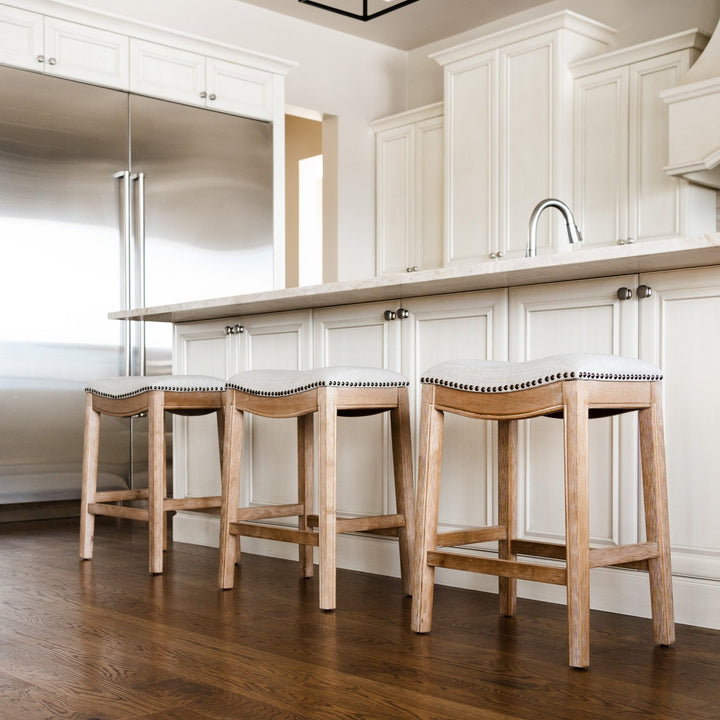 Adrien Saddle Counter Stool In Weathered Oak Finish With Sand Color Fabric Upholstery in Stools by Maven Lane