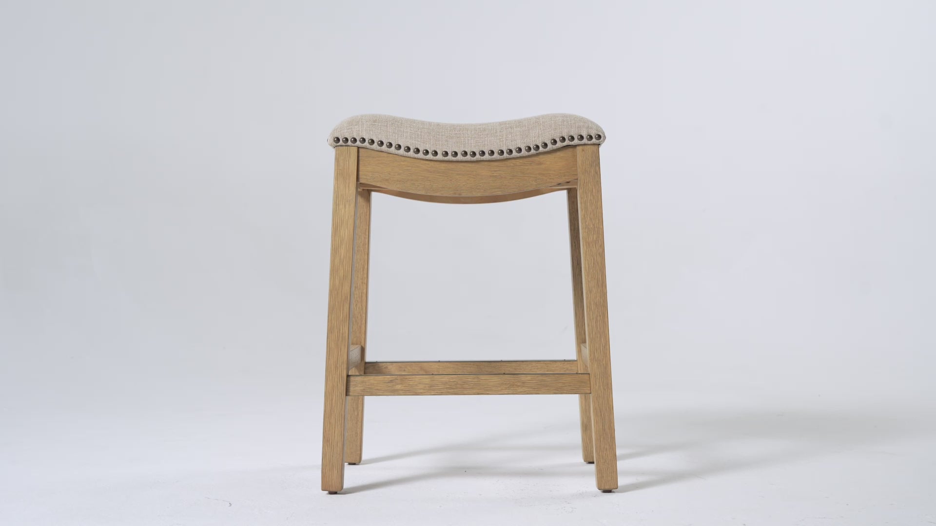 Adrien Saddle Counter Stool in Light Brown Finish and Natural Fabric Upholstery in Stools by Maven Lane